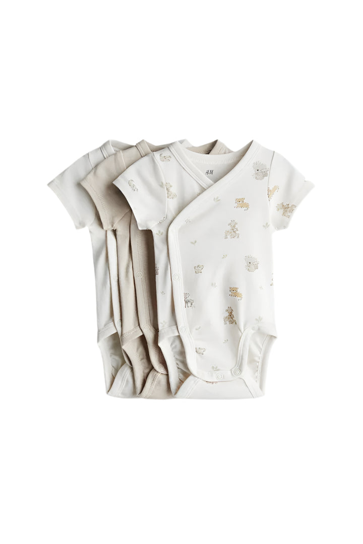 Two baby bodysuits, one beige and one white with floral pattern, on a light gray background.