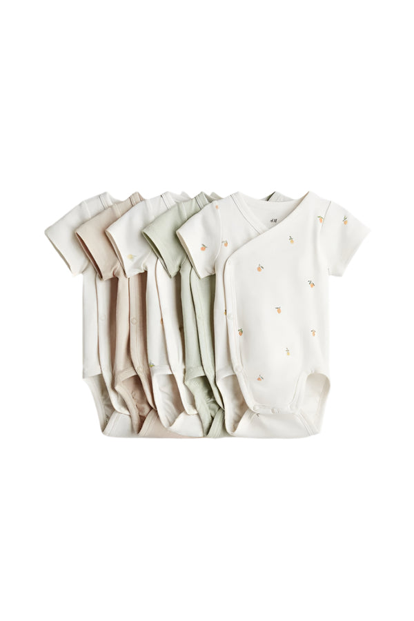 Set of baby bodysuits in various neutral colors on a light gray background